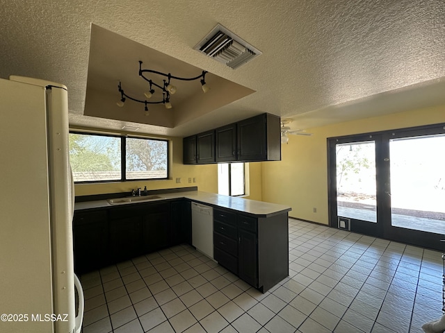 4241 E Aquarius Dr, Tucson, AZ 85718 - kitchen with white appliances, a peninsula, a sink, light tile patterned floors, and a textured ceiling