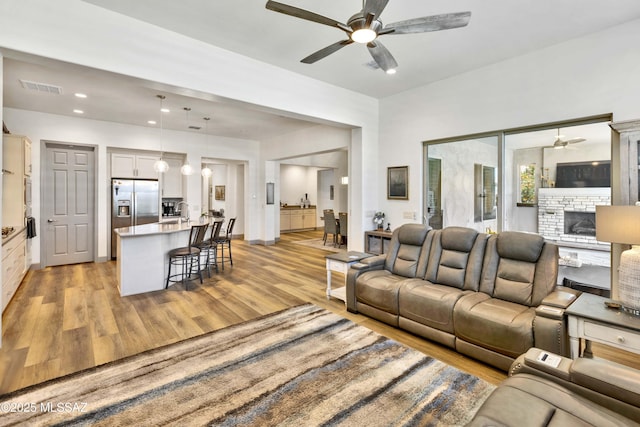 61672 E Talc St, Oracle, AZ 85623 - living room featuring a ceiling fan, light wood-style flooring, a fireplace, and recessed lighting
