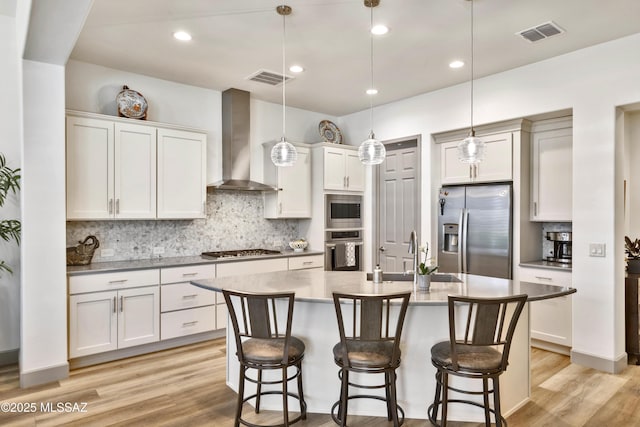 61672 E Talc St, Oracle, AZ 85623 - kitchen featuring stainless steel appliances, wall chimney exhaust hood, a sink, light wood finished floors, and tasteful backsplash