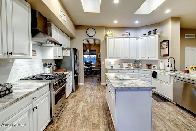 2500 N Fennimore Ave, Tucson, AZ 85749 - kitchen with stainless steel appliances, wall chimney exhaust hood, a center island, recessed lighting, and a skylight