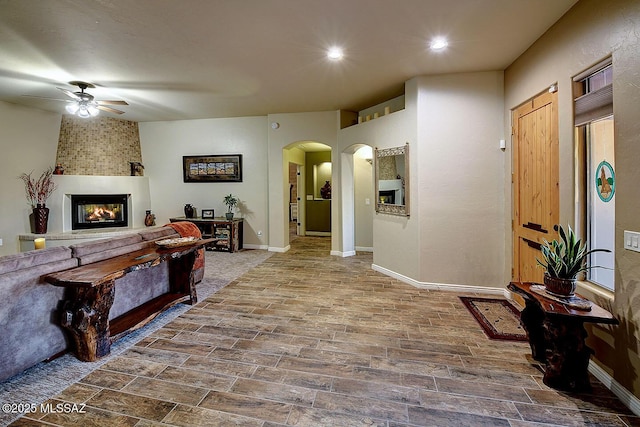 2500 N Fennimore Ave, Tucson, AZ 85749 - living room featuring arched walkways, a ceiling fan, a large fireplace, baseboards, and recessed lighting