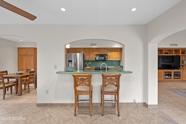 14488 N Rock Springs Ln, Oro Valley, AZ 85755 - kitchen with stainless steel fridge with ice dispenser, black microwave, arched walkways, range, and light tile patterned floors