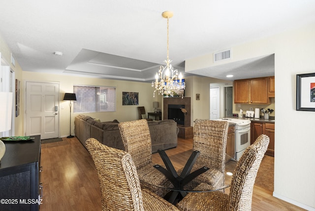 5051 N Sabino Canyon Rd Unit 1107, Tucson, AZ 85750 - dining area with wood finished floors, a fireplace with raised hearth, a chandelier, a tray ceiling, and baseboards