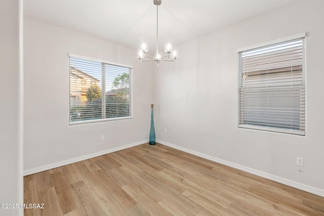 11358 W Folsom Point Dr, Marana, AZ 85658 - empty room featuring a chandelier, light wood-style flooring, and baseboards