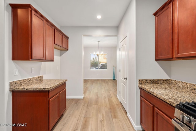 11358 W Folsom Point Dr, Marana, AZ 85658 - kitchen featuring light wood-style floors, a chandelier, stainless steel range with gas cooktop, baseboards, and light stone counters