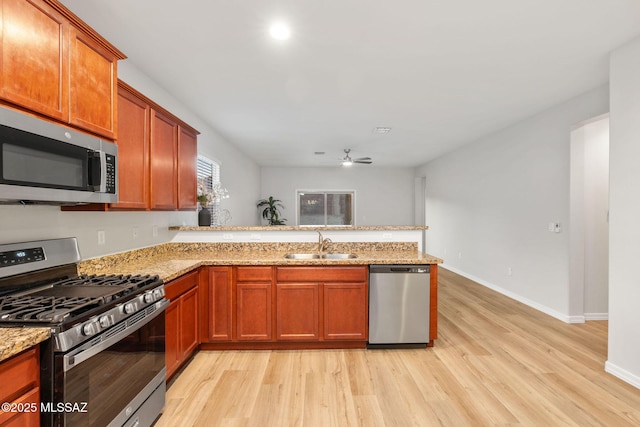 11358 W Folsom Point Dr, Marana, AZ 85658 - kitchen featuring appliances with stainless steel finishes, a sink, a peninsula, light wood-style floors, and ceiling fan