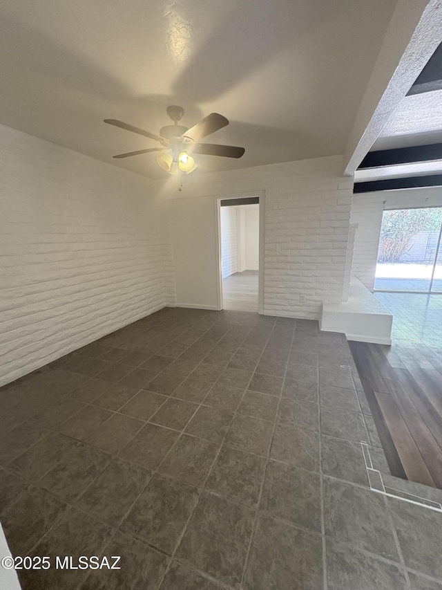 1166 Zircon Ct, Rio Rico, AZ 85648 - empty room featuring brick wall, a ceiling fan, and dark tile patterned floors