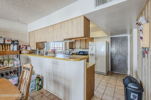 3090 W Alaska St, Tucson, AZ 85746 - kitchen featuring white fridge with ice dispenser, light tile patterned floors, light countertops, a textured ceiling, and a peninsula