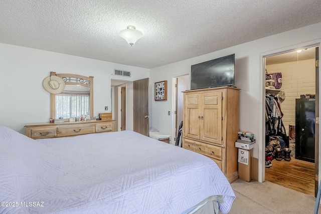 3090 W Alaska St, Tucson, AZ 85746 - bedroom featuring a walk in closet, a textured ceiling, a closet, and light carpet