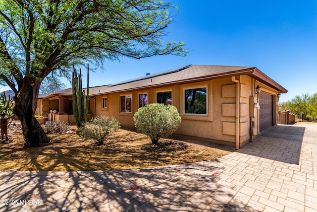 3740 W Placita Fantasia, Tucson, AZ 85745 - view of front facade featuring solar panels, stucco siding, decorative driveway, a garage, and roof with shingles