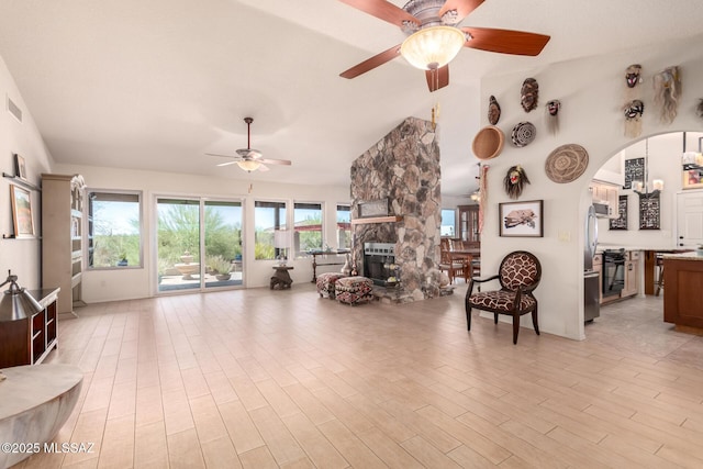 3740 W Placita Fantasia, Tucson, AZ 85745 - living area featuring a ceiling fan, vaulted ceiling, arched walkways, a fireplace, and light wood-style floors