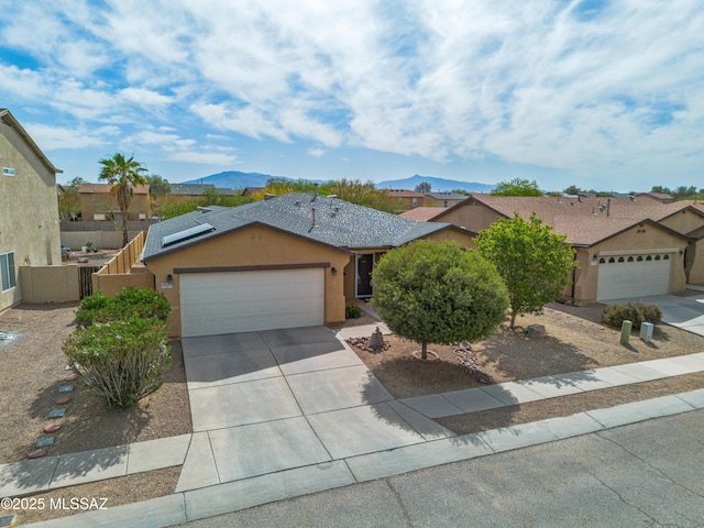6945 S Wingbow Dr, Tucson, AZ 85756 - ranch-style home featuring a garage, concrete driveway, stucco siding, solar panels, and a mountain view