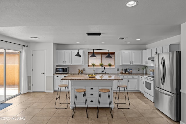 6945 S Wingbow Dr, Tucson, AZ 85756 - kitchen with appliances with stainless steel finishes, a sink, a breakfast bar area, tasteful backsplash, and a center island