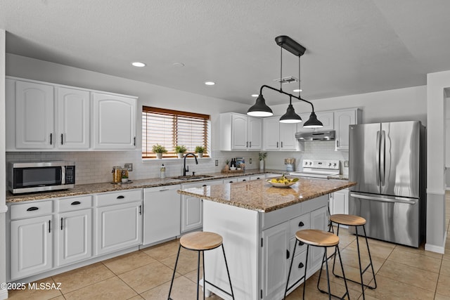 6945 S Wingbow Dr, Tucson, AZ 85756 - kitchen with appliances with stainless steel finishes, under cabinet range hood, a sink, a kitchen bar, and backsplash