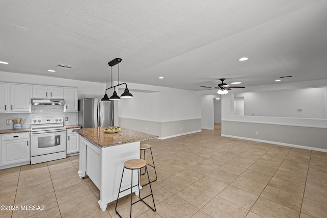 6945 S Wingbow Dr, Tucson, AZ 85756 - kitchen with white range with electric cooktop, freestanding refrigerator, under cabinet range hood, light tile patterned floors, and recessed lighting