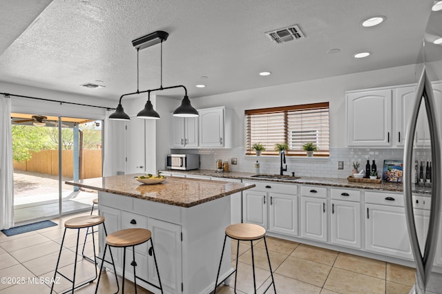 6945 S Wingbow Dr, Tucson, AZ 85756 - kitchen with a sink, stainless steel appliances, a breakfast bar, plenty of natural light, and a textured ceiling
