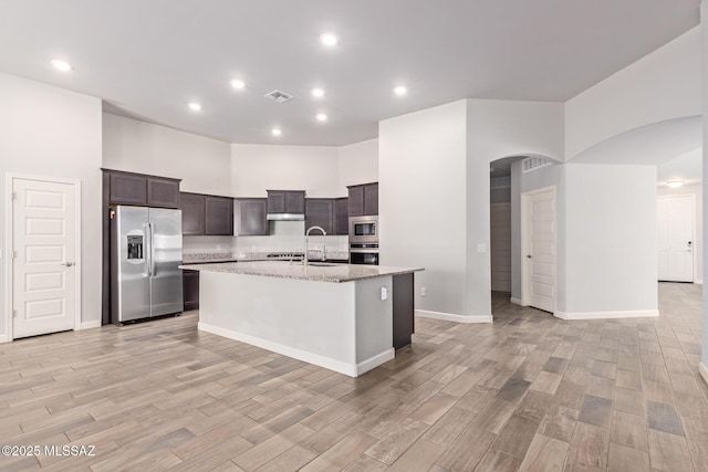 854 S Willis Ave, Vail, AZ 85641 - kitchen with appliances with stainless steel finishes, light wood-style floors, dark brown cabinets, an island with sink, and light stone counters