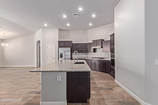 854 S Willis Ave, Vail, AZ 85641 - kitchen with stainless steel appliances, a sink, a kitchen island with sink, arched walkways, and light stone counters