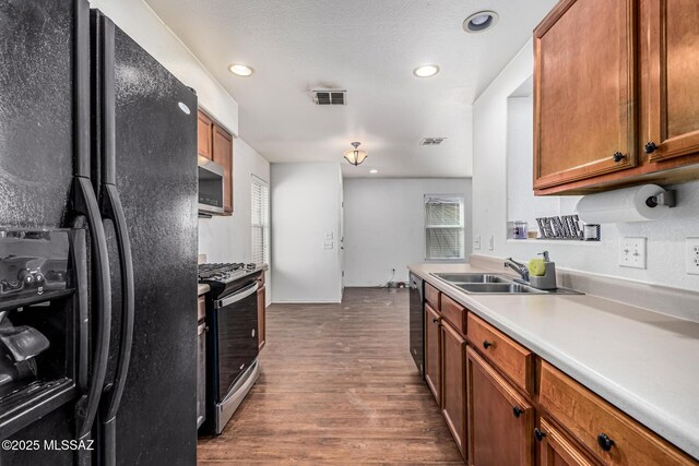 6399 S Sunrise Valley Dr, Tucson, AZ 85706 - kitchen featuring appliances with stainless steel finishes, a sink, brown cabinetry, wood finished floors, and light countertops