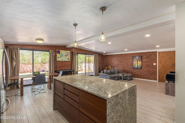 5809 E Rosewood St, Tucson, AZ 85711 - kitchen featuring brick wall, a center island, light wood-style flooring, lofted ceiling, and freestanding refrigerator