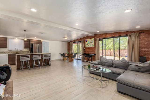 5809 E Rosewood St, Tucson, AZ 85711 - living room featuring brick wall, light wood-style flooring, and a textured ceiling