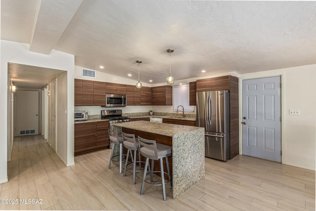 5809 E Rosewood St, Tucson, AZ 85711 - kitchen with appliances with stainless steel finishes, a sink, light wood finished floors, a kitchen island, and recessed lighting