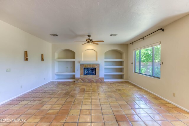 7275 E Vuelta Rancho Mesquite, Tucson, AZ 85715 - unfurnished living room featuring built in features, baseboards, a tiled fireplace, and light tile patterned flooring