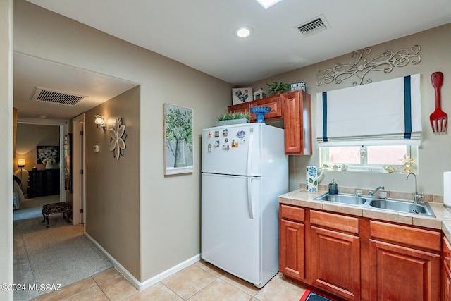 6255 N Camino Pimeria Alta Unit 22, Tucson, AZ 85718 - kitchen featuring freestanding refrigerator, a sink, light tile patterned flooring, brown cabinetry, and tile countertops