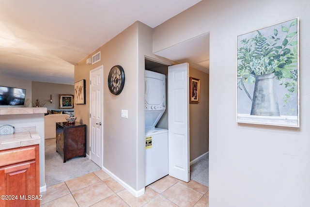 6255 N Camino Pimeria Alta Unit 22, Tucson, AZ 85718 - hallway with stacked washer and clothes dryer, light tile patterned floors, baseboards, and light carpet