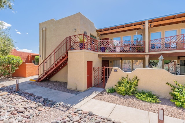 6255 N Camino Pimeria Alta Unit 22, Tucson, AZ 85718 - view of front of house with stucco siding, a balcony, a gate, and stairway