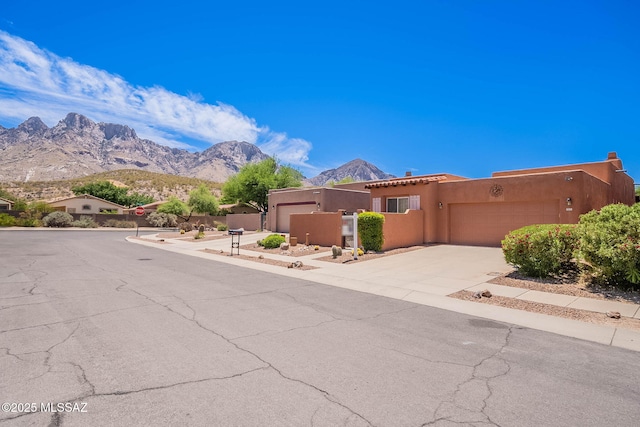 11315 N Mountain Meadow Pl, Oro Valley, AZ 85737 - pueblo revival-style home with an attached garage, driveway, stucco siding, and a mountain view