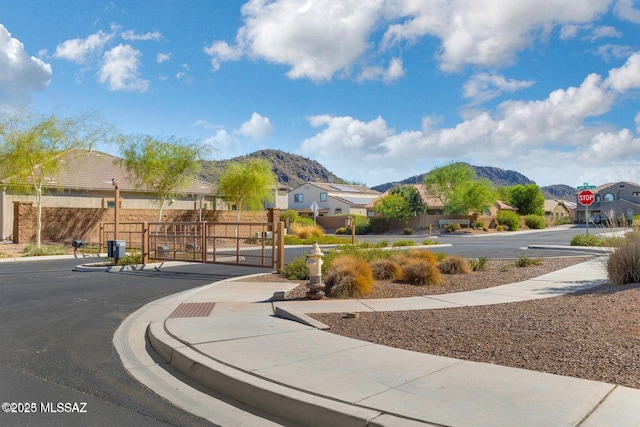 8880 W Blakebrook Rd, Marana, AZ 85653 - view of asphalt street with sidewalks, a mountain view, traffic signs, a residential view, and a gate