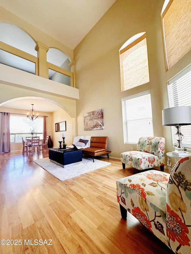 15415 S Camino Agua Azul, Sahuarita, AZ 85629 - living room featuring a chandelier, a high ceiling, wood finished floors, and arched walkways