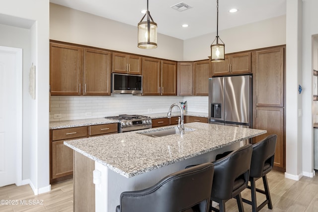 62146 E Marble Dr, Oracle, AZ 85623 - kitchen featuring appliances with stainless steel finishes, a sink, light wood-style floors, a breakfast bar area, and decorative backsplash