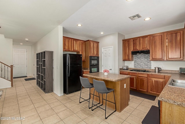 7952 E Revolution Loop, Tucson, AZ 85730 - kitchen featuring black appliances, light tile patterned floors, a center island, tasteful backsplash, and brown cabinets