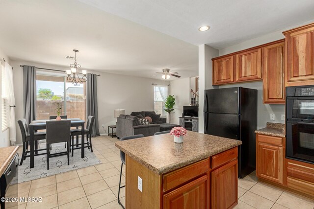 7952 E Revolution Loop, Tucson, AZ 85730 - kitchen with black appliances, brown cabinets, a chandelier, light tile patterned flooring, and a center island
