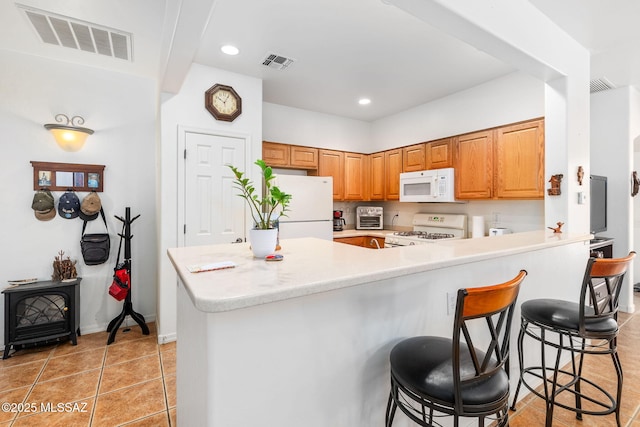 731 W Calle Montero, Sahuarita, AZ 85629 - kitchen featuring white appliances, a kitchen bar, light countertops, light tile patterned flooring, and recessed lighting