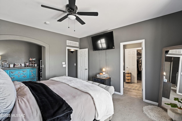3630 W Center Mountain Way, Tucson, AZ 85746 - bedroom with light colored carpet, a walk in closet, a ceiling fan, and arched walkways