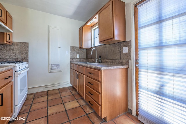 318 N Fremont Ave, Tucson, AZ 85719 - kitchen featuring white gas range, a sink, decorative backsplash, under cabinet range hood, and brown cabinetry