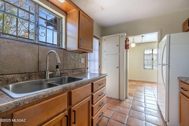318 N Fremont Ave, Tucson, AZ 85719 - kitchen featuring freestanding refrigerator, a sink, brown cabinetry, light tile patterned floors, and decorative backsplash