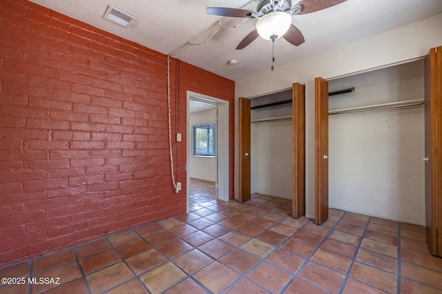 318 N Fremont Ave, Tucson, AZ 85719 - unfurnished bedroom featuring two closets, brick wall, ceiling fan, and tile patterned floors