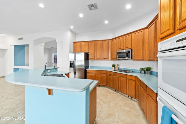 35 N Monument Estates Pl, Tucson, AZ 85748 - kitchen featuring a sink, appliances with stainless steel finishes, brown cabinets, arched walkways, and light tile patterned floors
