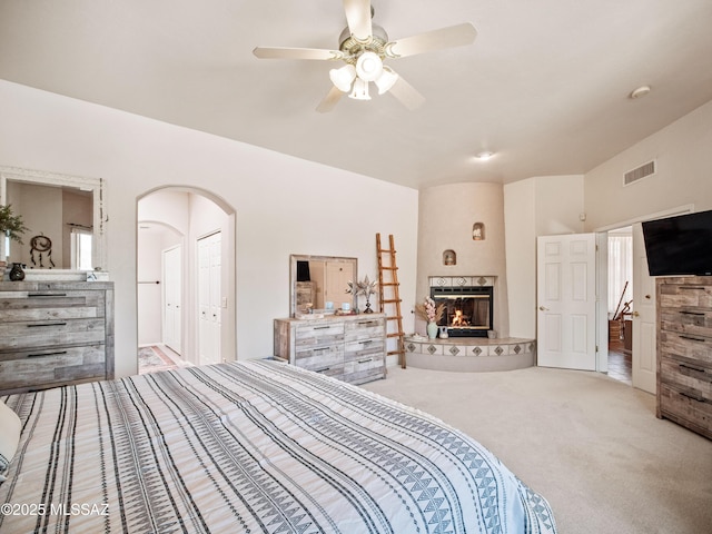 5475 E Placita De Royale, Tucson, AZ 85718 - carpeted bedroom with arched walkways, a warm lit fireplace, and connected bathroom