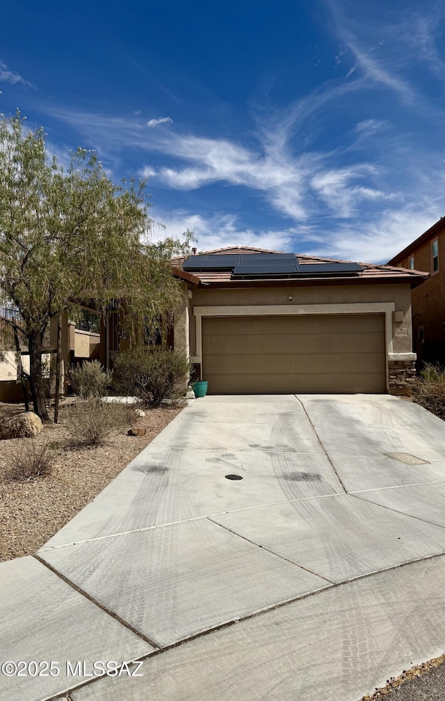 16038 S Camino Casal, Sahuarita, AZ 85629 - view of front facade with driveway, a garage, solar panels, stucco siding, and stone siding