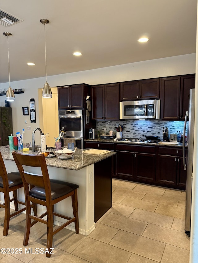 16038 S Camino Casal, Sahuarita, AZ 85629 - kitchen with appliances with stainless steel finishes, decorative backsplash, a kitchen breakfast bar, dark stone counters, and recessed lighting