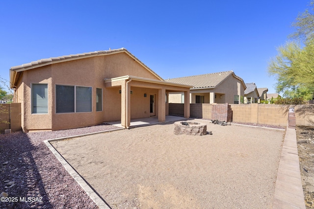 10393 Yew Pl, Tucson, AZ 85747 - back of house featuring an outdoor fire pit, stucco siding, a fenced backyard, and a patio