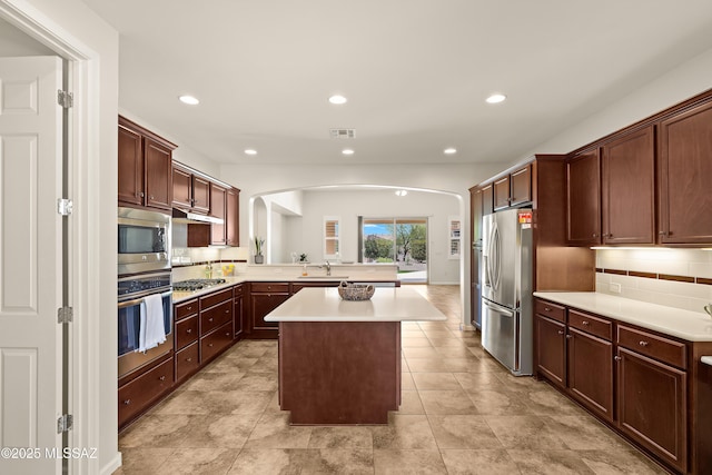 61050 E Amur Ln, Oracle, AZ 85623 - kitchen with stainless steel appliances, arched walkways, a sink, tasteful backsplash, and light countertops