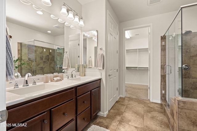 61050 E Amur Ln, Oracle, AZ 85623 - bathroom featuring double vanity, a stall shower, a spacious closet, tile patterned floors, and baseboards