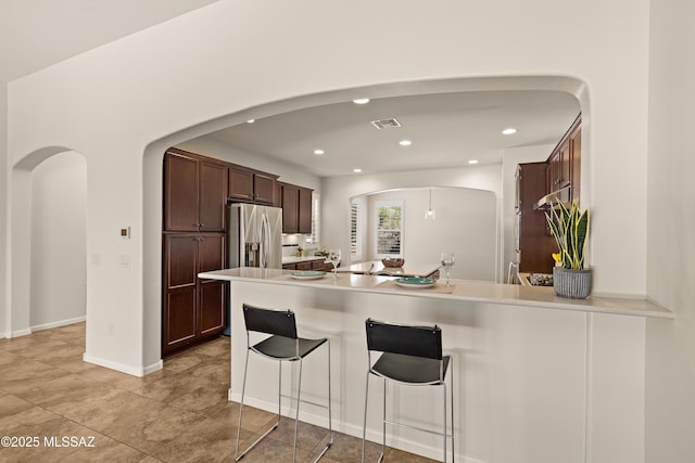 61050 E Amur Ln, Oracle, AZ 85623 - kitchen featuring arched walkways, stainless steel refrigerator with ice dispenser, recessed lighting, a peninsula, and a breakfast bar