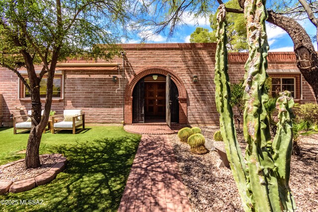 6945 N Mona Lisa Rd, Tucson, AZ 85741 - view of exterior entry with french doors, brick siding, and a lawn